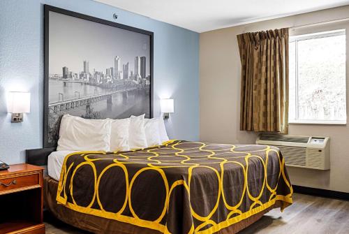 a hotel room with a bed with a yellow and black blanket at Super 8 by Wyndham Pittsburgh/Monroeville in Monroeville