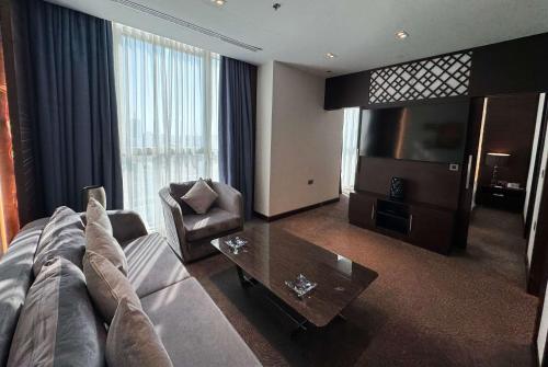 a living room with a couch and a table and a television at Ramada Encore Doha by Wyndham in Doha