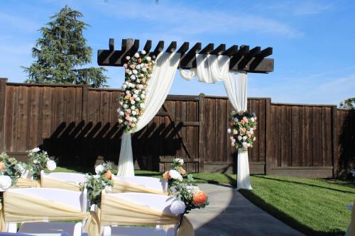 a wedding arch with white chairs and flowers at Hilton Sacramento Arden West in Sacramento