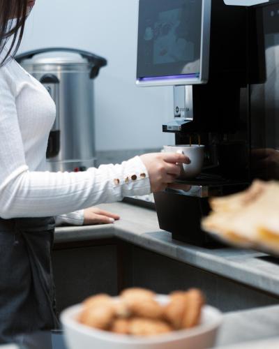 a woman is making a cup of coffee in a kitchen at Dynasty Hotel & SPA in Yerevan