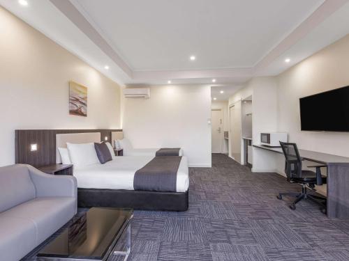 a hotel room with a bed and a desk at Quality Hotel Melbourne Airport in Melbourne