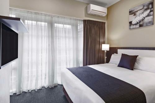 a hotel room with a bed and a large window at Quality Hotel Melbourne Airport in Melbourne