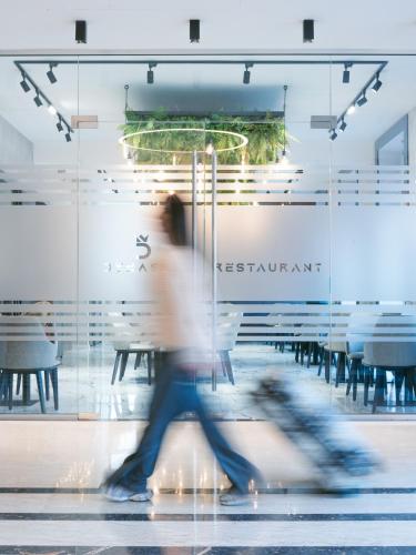 a person walking past a restaurant with a wall of glass at Dynasty Hotel & SPA in Yerevan