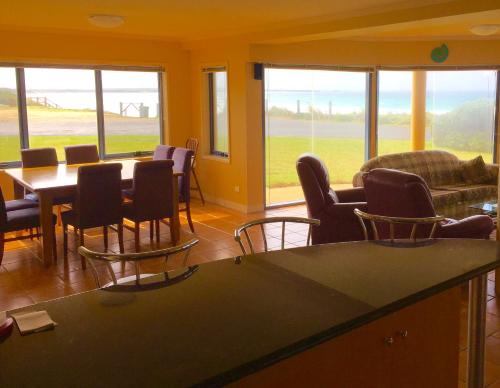 a living room with a table and chairs and windows at Horizons Beachfront Apartment in Port Fairy