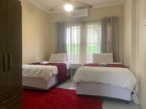 two beds in a room with a red carpet at The Prayer and Family Guesthouse in Durban