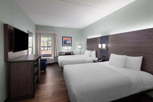 a hotel room with two beds and a flat screen tv at Baymont by Wyndham Creedmoor in Creedmoor