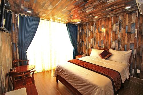 1 dormitorio con 1 cama con pared de madera en Nest Hotel, en Ho Chi Minh