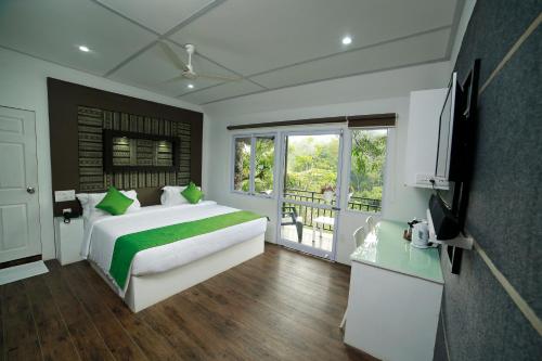a bedroom with a large bed and a television at Moselberg Riverside Cottages in Munnar