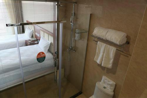a bathroom with a shower with a toilet and towels at GreenTree Inn Beijing Fangshan Liangxiang Suzhuang Express Hotel in Fangshan