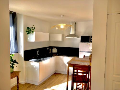 une cuisine avec des armoires blanches et une table avec des chaises dans l'établissement Appartement Tout Confort Coeur de Ville Grand Balcon Le Néouvielle, à Bagnères-de-Bigorre