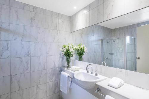 een witte badkamer met een wastafel en een spiegel bij Cathedral Motor Inn in Bendigo
