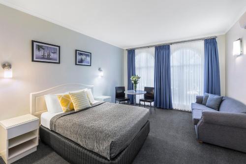 um quarto de hotel com uma cama, um sofá e uma cadeira em Cathedral Motor Inn em Bendigo