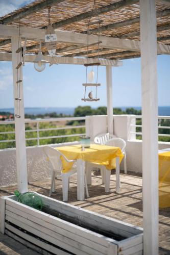 a patio with a yellow table and chairs and the ocean at Gariga Holidays Apartments in Nardò
