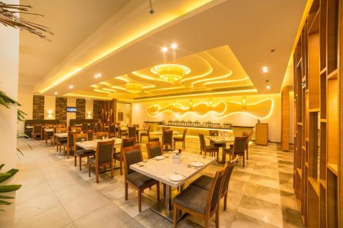 a restaurant with tables and chairs in a room at Hotel Vivera Grande in Dindigul