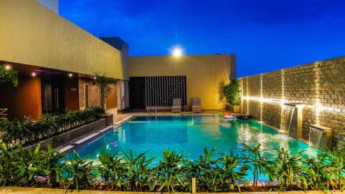 uma piscina em frente a um edifício à noite em Hotel Vivera Grande em Dindigul
