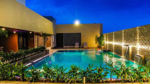a swimming pool in front of a building at night at Hotel Vivera Grande in Dindigul