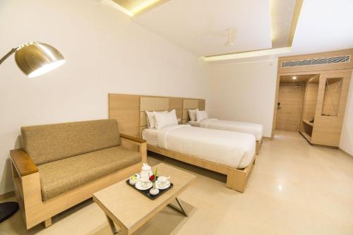 um quarto de hotel com uma cama e um sofá em Hotel Vivera Grande em Dindigul