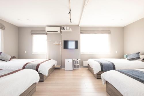 a bedroom with three beds and a tv in it at Tokuno Zoo Street in Asahikawa