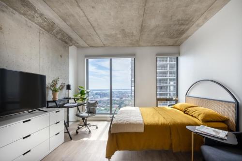 a bedroom with a yellow bed and a large window at Appartements Dorchester in Montreal