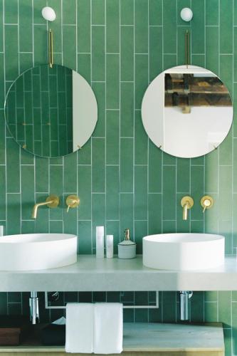two sinks in a green tiled bathroom with mirrors at Portside Inn Hakodate in Hakodate