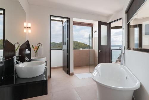 een badkamer met 2 wastafels en een bad bij Busuanga Bay Lodge in Busuanga
