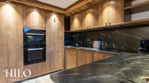 a kitchen with wooden cabinets and a black counter top at Hilo Suite Val d Isere Gelinotte avec Jacuzzi in Val dʼIsère