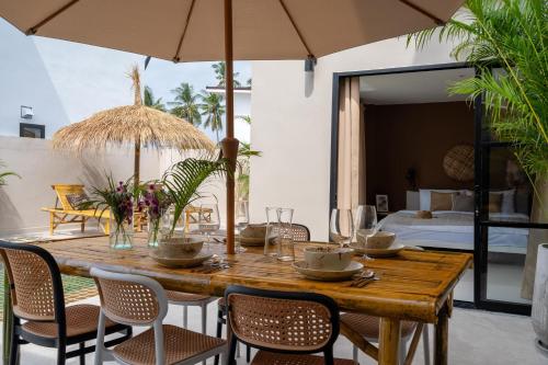 a wooden table with chairs and an umbrella at Manao Seaview Pool Villa38A - 5Mins Walk To Beach in Ko Lanta