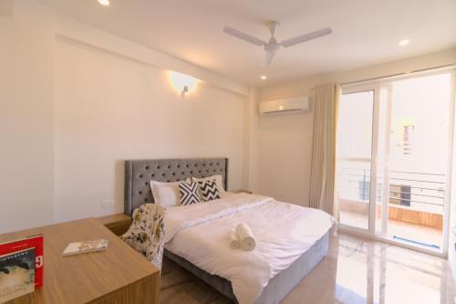 a bedroom with a bed and a desk and a window at Liv Regalia - One Horizon Centre Golf Course Road in Gurgaon
