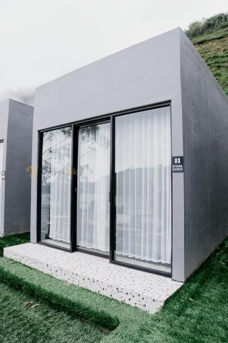 a building with large windows and green grass at Stigma Kubus By Travelink in Kejajar
