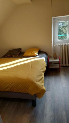 a bedroom with a bed with yellow sheets and a window at Maison spacieuse à Montsalvy avec grand jardin et terrasse in Montsalvy
