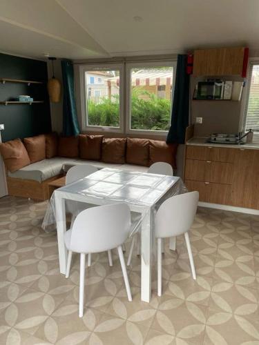 un salon avec une table et des chaises blanches dans l'établissement Mobile home au calme et paisible, aux Mathes