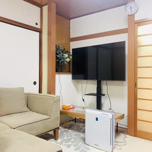 a living room with a couch and a flat screen tv at Japan House 湯島 in Tokyo