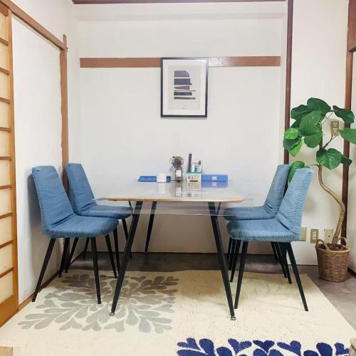 a dining room table with blue chairs and a plant at Japan House 湯島 in Tokyo