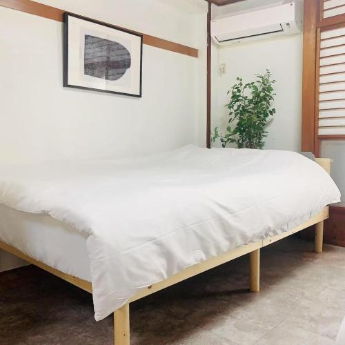 a bedroom with a bed with white sheets and a plant at Japan House 湯島 in Tokyo