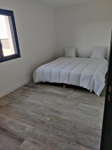 Ce lit se trouve dans une chambre blanche dotée d'un sol. dans l'établissement Location au calme, à Saint-Paul-Trois-Châteaux