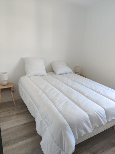 un grand lit blanc avec des draps et des oreillers blancs dans l'établissement Location au calme, à Saint-Paul-Trois-Châteaux