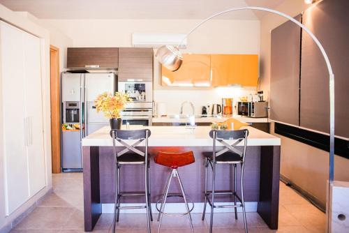 a kitchen with a kitchen island with two stools at Villas On The Rock Afissos in Afissos