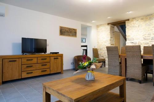 a living room with a television on a wooden dresser at Gîtes de l'Orée du Bois - Torpes in Torpes