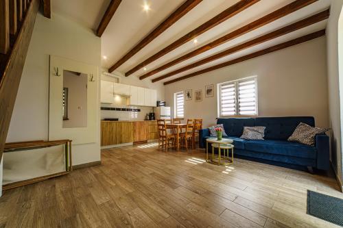 a living room with a blue couch and a kitchen at Apartamenty Koło Brzegu in Gąski