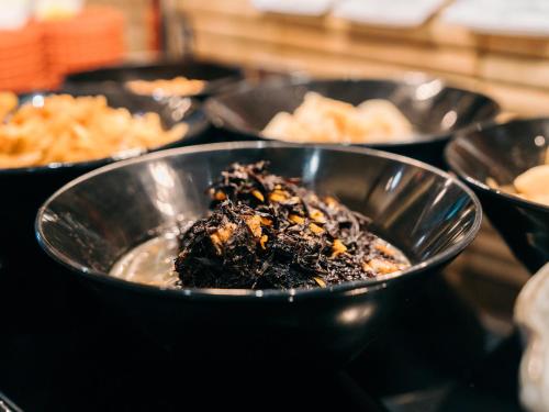 a group of black bowls filled with food on a table at Hearton Hotel Kita Umeda in Osaka