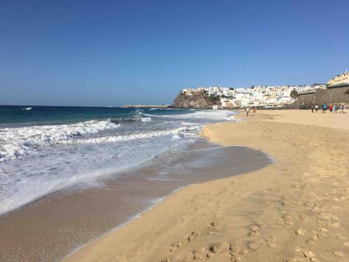 a beach with people walking on the sand and the ocean at Villa Barry Swimming Pool, Amazing Sea Views, Bar in Tarajalejo