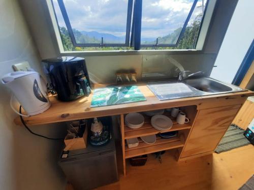 a kitchen counter with a sink and a window at Mountain view Bespoke tiny home in Plettenberg Bay