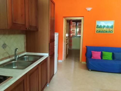 a kitchen with a sink and a blue couch at Villette di Scopello - Casa Vacanze in Scopello