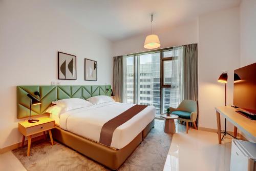 a hotel room with a large bed and a window at Capital Suites Hotel Apartments in Abu Dhabi