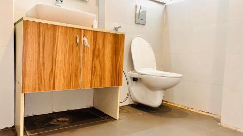 グルガオンにあるLiv Regalia - Rapid Metro Phase 1 Gurgaonのバスルーム(トイレ付)、木製キャビネットが備わります。