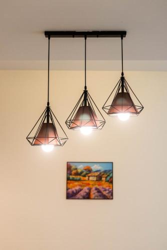 three lights hanging from a ceiling with a picture at Comfy Sunset View Home with Swimming Pool & Netflix in Taiping