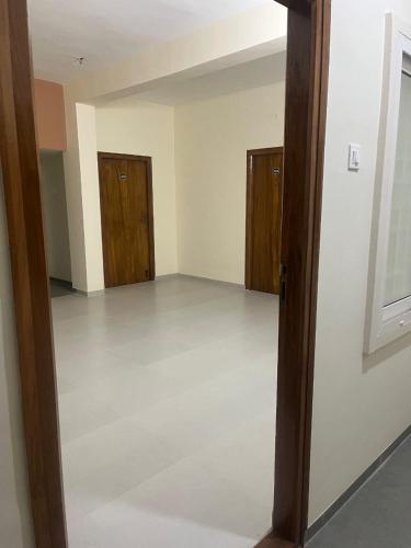 an empty room with wooden doors and a white floor at Subam Residency in Singānallūr