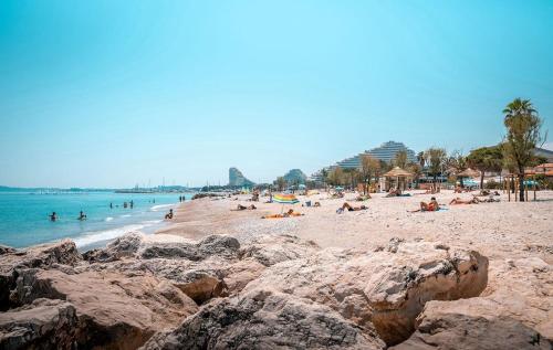 a beach with people laying on the sand and the water at Appartement vue mer tout confort in Villeneuve-Loubet