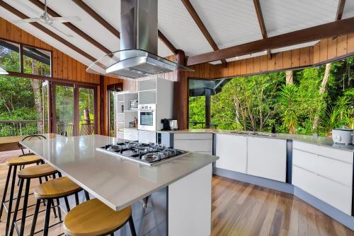a kitchen with white cabinets and a counter with stools at Pole home in paradise at Kuranda in Kuranda