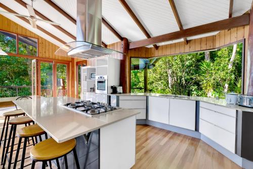 a kitchen with white cabinets and a counter with stools at Pole home in paradise at Kuranda in Kuranda
